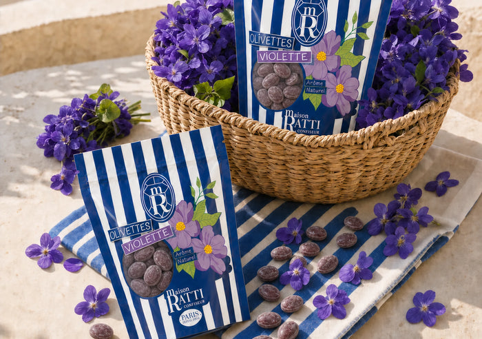 Bags of Maison Ratti violet olivettes in a wicker basket, surrounded by fresh violets